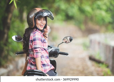 A Portrait Of A Young Asian Woman Riding A Motorcycle In A Park