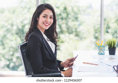 Portrait Young Asian Woman Smile In Office Holding Smartphone Green Nature Bokeh Background.  