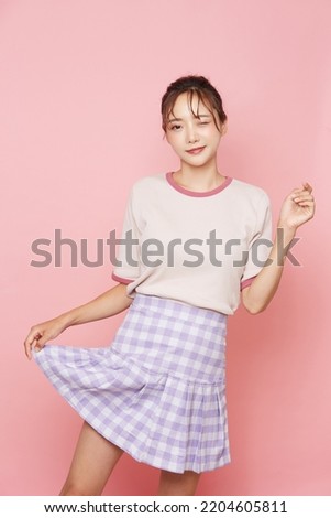 Portrait of young Asian woman in sporty fashion on pink background