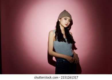 Portrait of young Asian woman in street fashion on pink background