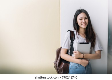 Portrait of young Asian woman student using a laptop or tablet in smart and happy pose at university or college, Youth girl student and tutoring education with technology learning concept.