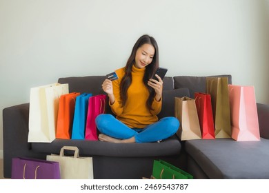 Portrait young asian woman using laptop computer with smart mobile phone and credit card for online shopping in living room - Powered by Shutterstock