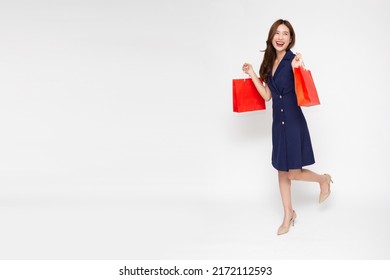 Portrait Of Young Asian Woman Walking And Holding Shopping Bag Isolated Over White Background, Full Body Composition