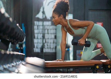 Portrait of young athlete black woman raised dumbbell exercise with concentrate and confident expression face. Lifestyle workout for women to lean muscular healthcare trending. - Powered by Shutterstock