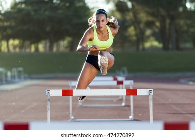 Portrait of young athlete jumping over a hurdle during training on race track. - Shutterstock ID 474270892