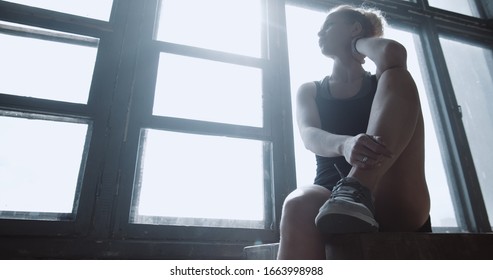 Portrait Of Young Athletic Blonde Woman Sitting Exhausted And Breathing Heavy After Power Training In Gym Slow Motion.