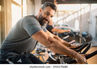 Portrait of a Young athletic man in sportswear doing cycling on exercise bikes at the gym - Powered by Shutterstock