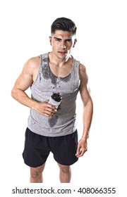 Portrait Of Young Athletic Sport Man Thirsty Holding Bottle Of Water  With Sweaty Face And Wet Singlet After Refreshing And Recovering After Hard Training Workout In Hydration Concept