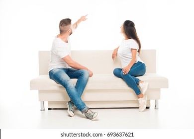 'portrait Of Young Attractive Couple Sitting On Couch And Looking On Something Away Back, Isolated On White