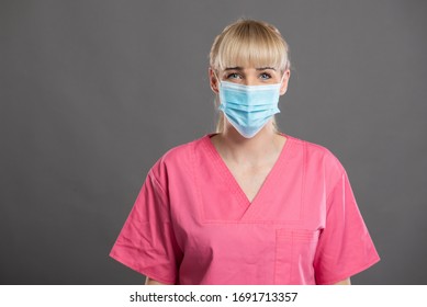 Portrait von jungen attraktiven weiblichen Krankenschwestern mit Gesichtsmaske auf grauem Hintergrund mit Werbespot