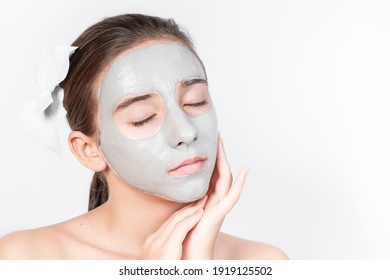Portrait of a young attractive girl with a cosmetic mask on her face. Close-up. Face skin care concept.Beautiful girl with a cosmetic mask made of clay on her face. Cosmetic procedures.