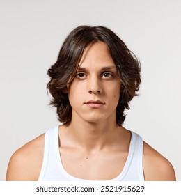 Portrait of young attractive man with long brunette hair and well-kept skin looking at camera calmly against white studio background. Concept of natural beauty, fashion, cosmetic product, male health. - Powered by Shutterstock