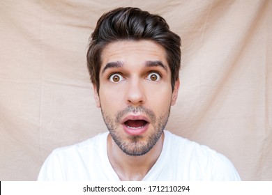 Portrait Of A Young Attractive Man With A Shock Face And Wide Open Eyes And Mouth