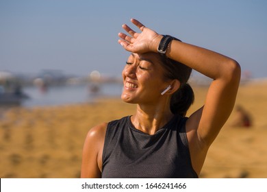 Portrait Of Young Attractive And Sweaty Happy Asian Indonesian Woman In Her 40s Smiling Satisfied After Hard Beach Running Workout In Sports Training And Healthy Lifestyle Concept