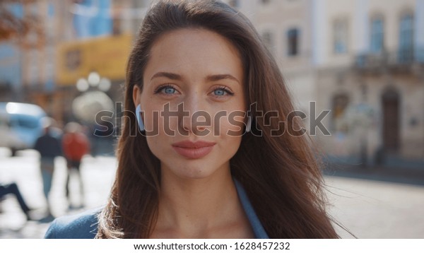 Portrait young attractive woman with blue eyes look\
at camera serious at city center attractive style walking hair\
outdoor fashion girl summer face technology sun beautiful slow\
motion. The best