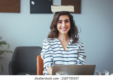 Portrait Of A Young Attractive Woman At The Desk With Books On Her Head, Sitting Straight, Working On Laptop. Education Concept Photo, Lifestyle. 