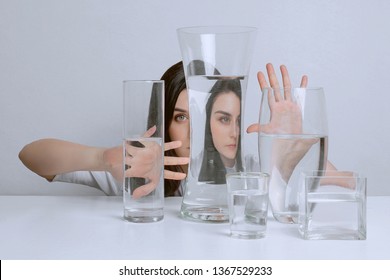 Portrait Of Young Attractive Woman. Distorted Reflection In Glass Vases With Water.