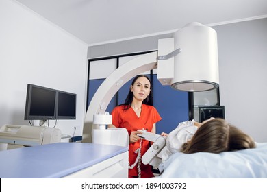 Portrait of young attractive woman doctor, looking at camera, while providing lithotripsy procedure and ultrasound scan for her female Caucasian patient with modern ultrasonic lithotriptor