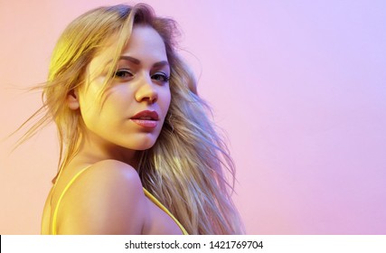 Portrait of a young attractive woman. Girl with long blond hair. Colorful bright light. Copy space.