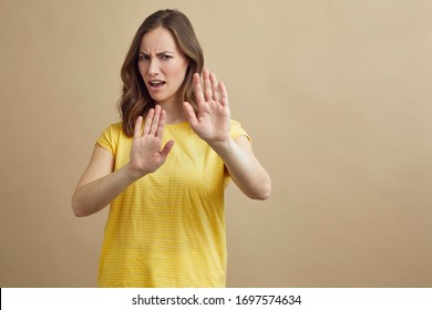 Portrait Of Young Attractive Woman Holding Her Hands Up In Front Of The Viewer To Signal 