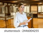 Portrait of young attractive woman with information booklet visiting archaeological museum