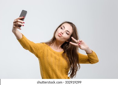 Portrait of a young attractive woman making selfie photo on smartphone isolated on a white background
