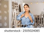 Portrait of young attractive woman standing at stepladder in apartment during repair works.