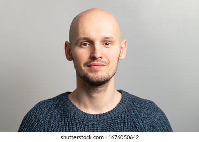 Portrait Of A Young Bald Man In A Knitted Sweater On A Gray Background