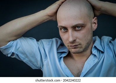 Portrait Of A Young Bald Man In A Shirt With His Hands Behind His Head And A Provocative Look