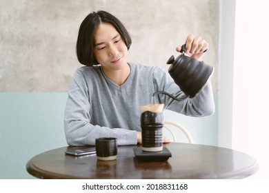 Portrait Of Young Barista Asian Man With Smile Makes Hot Coffee With Equipment ,tool Brewing On Bar At Table In His Home. Holiday Activity And Lifestyle Concept.