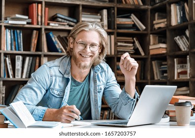 Portrait Young Bearded Male College Student Glasses Sit At Home Library Desk Handwrite Notebook Hold Pen Make Notes From Textbook Laptop Prepare Project Study Online Exam Test Web E Education Concept.