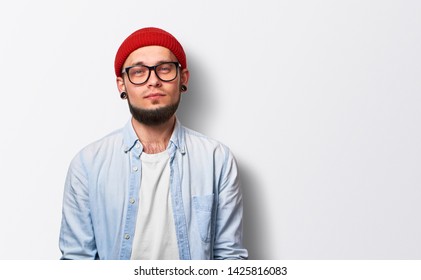 Portrait of young bearded man. Hipster boy. Handsome man in hat. Brutal bearded boy with tunnels and piercing over gray background - Shutterstock ID 1425816083