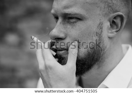 portrait of young bearded red hair man with sigaret black and white horizontal