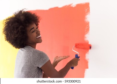 Portrait Of A Young Beautiful African American Woman Painting Wall In Her New Apartment