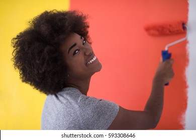 Portrait Of A Young Beautiful African American Woman Painting Wall In Her New Apartment