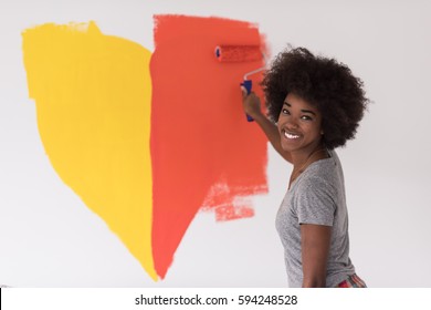 Portrait Of A Young Beautiful African American Woman Painting Wall In Her New Apartment