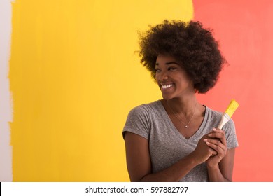 Portrait Of A Young Beautiful African American Woman Painting Wall In Her New Apartment