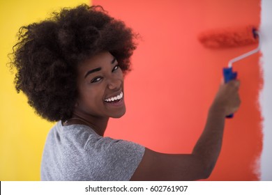 Portrait Of A Young Beautiful African American Woman Painting Wall In Her New Apartment