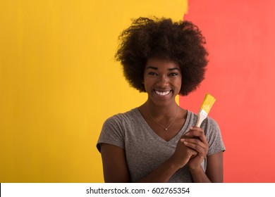 Portrait Of A Young Beautiful African American Woman Painting Wall In Her New Apartment