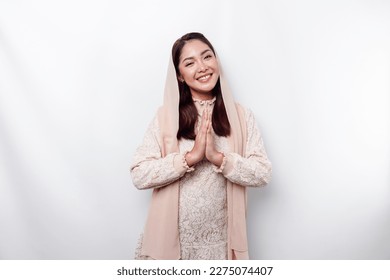 Portrait of a young beautiful Asian Muslim woman wearing a hijab gesturing Eid Mubarak greeting - Shutterstock ID 2275074407