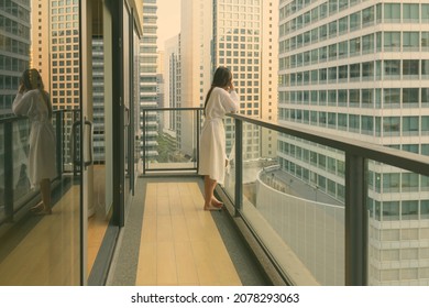 Portrait of young beautiful Asian woman enjoying the view of the city from the balcony - Powered by Shutterstock