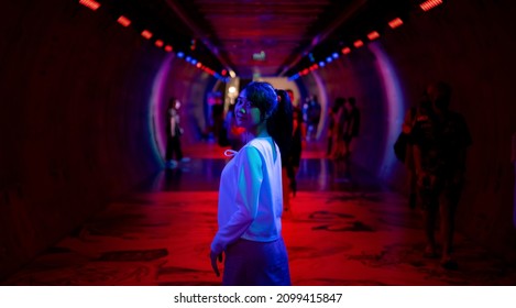 Portrait Of Young Beautiful Asian Woman Walking Down City Street And Subway Walk Way With Illuminated Neon Night Lights. Happy Pretty Girl Enjoy Urban Outdoor Lifestyle On Summer Vacation Nightlife