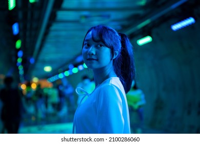 Portrait Of Young Beautiful Asian Woman Walking Down City Street And Subway Walk Way With Illuminated Neon Night Lights. Happy Pretty Girl Enjoy Urban Outdoor Lifestyle On Summer Vacation Nightlife