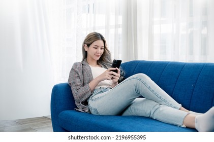 Portrait Of Young Beautiful Asian Woman Relax Use Smartphone Gadget On Sofa. Smile Happy Asian Girl Online Shopping Work From Home. Education E-commerce Freelance Technology Sme Connected Asia People