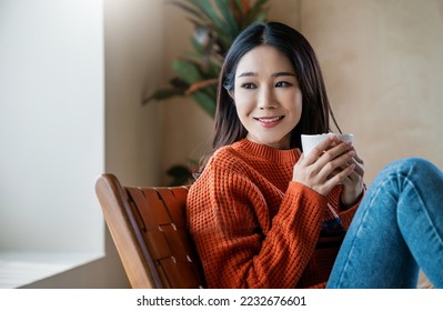Portrait of young beautiful asian woman in sweater hands holding a cup of marsh mellow coffee morning winter time relax at home. Happy cheerful relaxing cold winter, barista lifestyle, holiday banner - Shutterstock ID 2232676601
