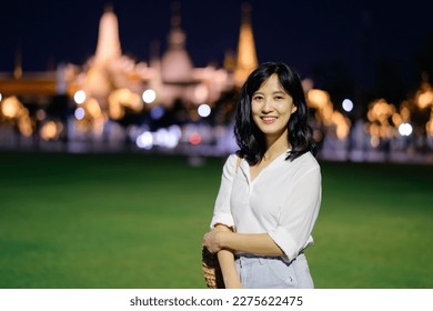 Portrait young beautiful asian woman smiling while travel at Temple of the Emerald Buddha or Wat Phra Kaew in night view point, Bangkok.