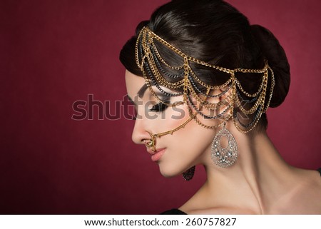 Portrait of young beautiful asian woman with evening make-up wearing head accessories over dark red background