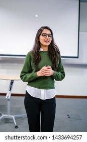 Portrait Of A Young, Beautiful, Attractive And Intelligent-looking Indian Asian Woman Wearing Spectacles In A Sweater Giving A Business Presentation To An Audience. 