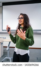 Portrait Of A Young, Beautiful, Attractive And Intelligent-looking Indian Asian Woman Wearing Spectacles In A Sweater Giving A Business Presentation To An Audience. 