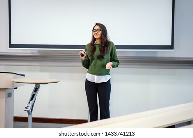 Portrait Of A Young, Beautiful, Attractive And Intelligent-looking Indian Asian Woman Wearing Spectacles In A Sweater Giving A Business Presentation To An Audience. 